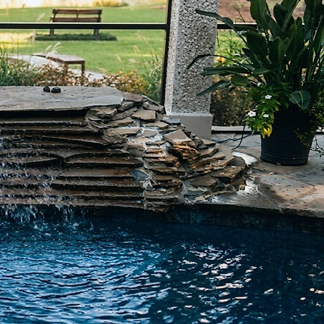 A stone waterfall feature at the edge of a shotcrete pool
