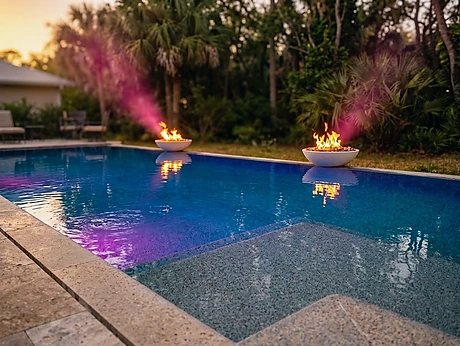 A Camp Pool Builders pool at dusk, fire bowls lit along the far edge